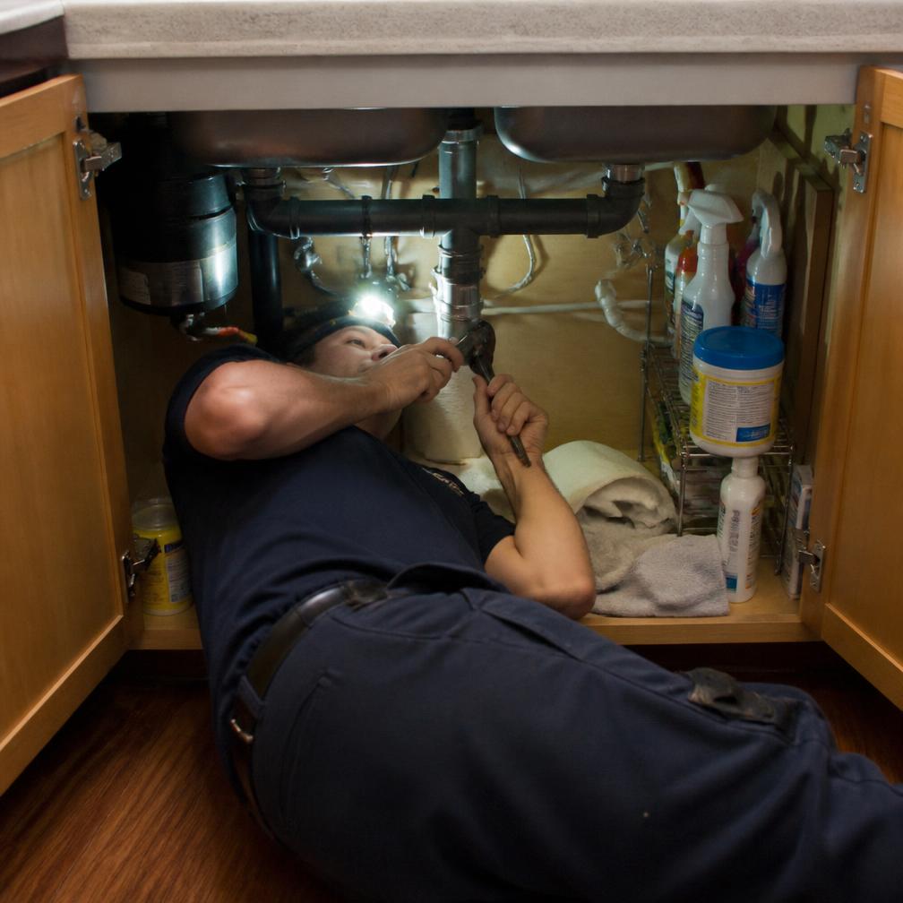 Plumber repairing a P-trap under a kitchen sink in Tupelo, MS